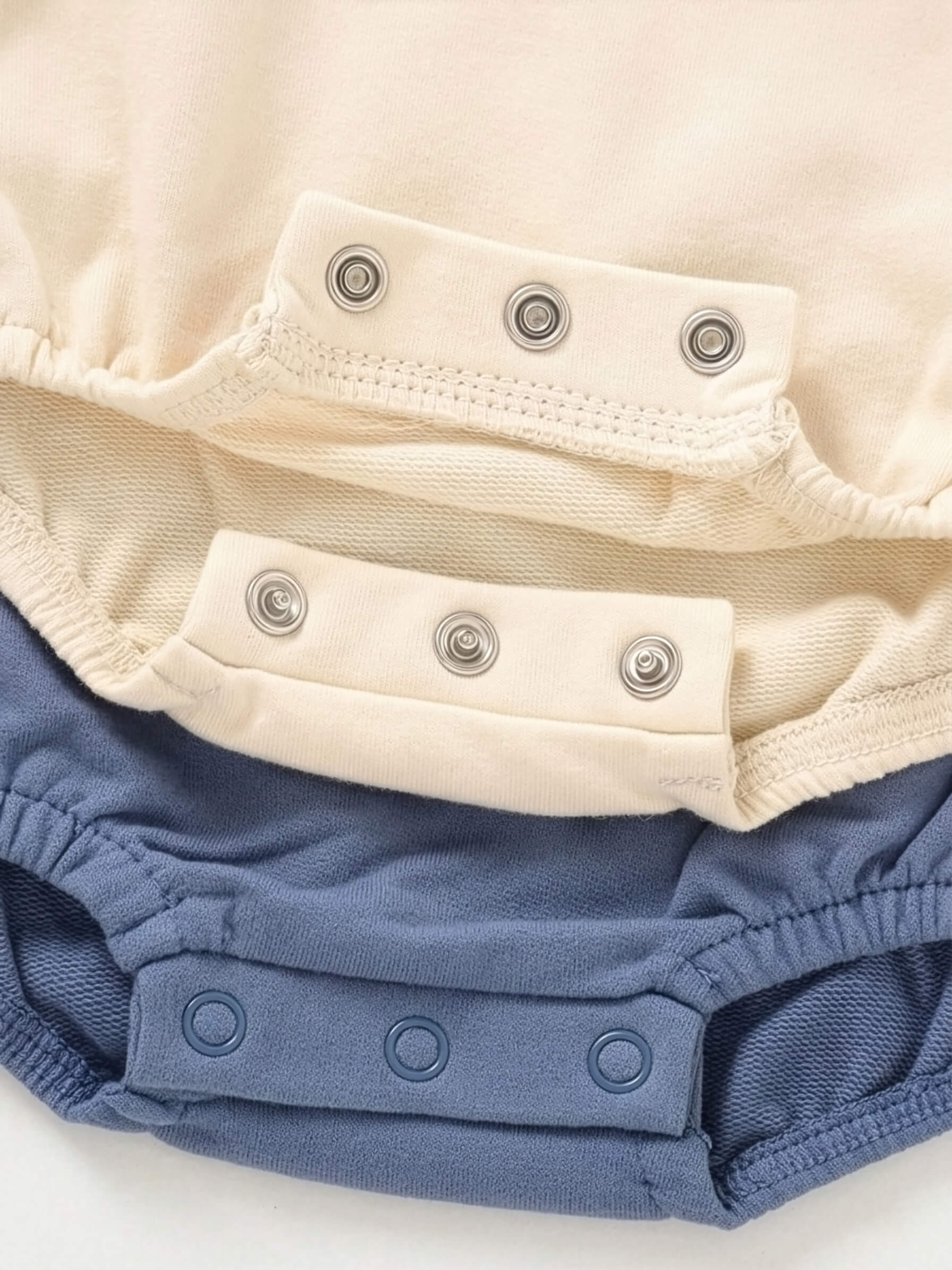Close-up of a baby romper with blue cover and beige lining on a white background
